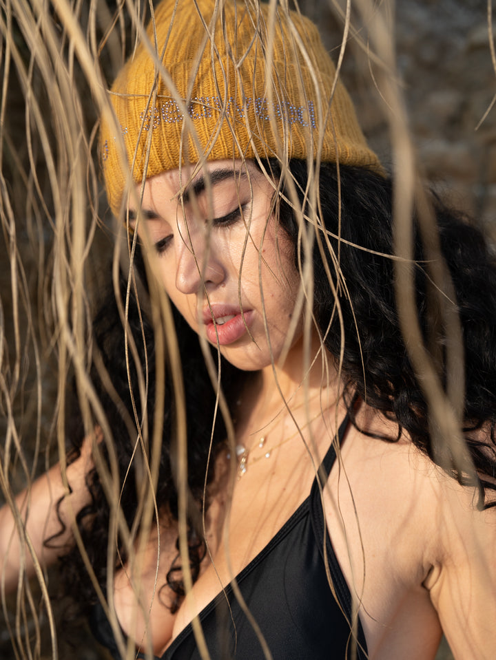 girl on beach wearing orange beanie with pink rhinestones